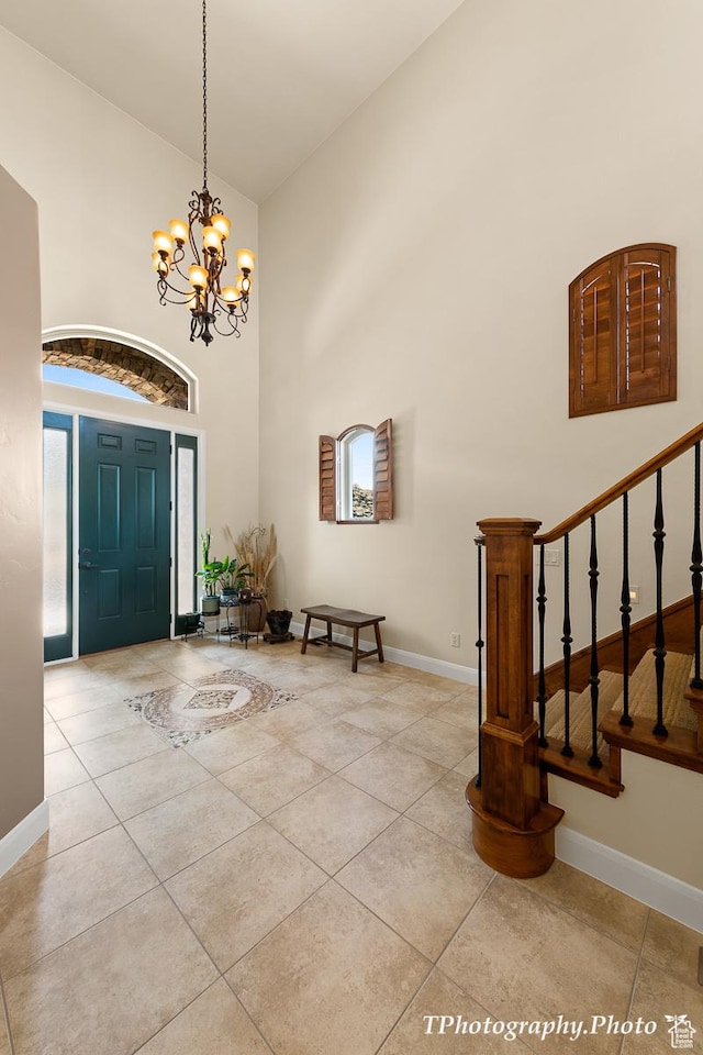entryway with a notable chandelier, light tile patterned floors, and a high ceiling
