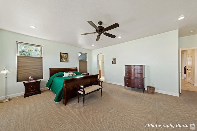 bedroom featuring a textured ceiling, light colored carpet, and ceiling fan