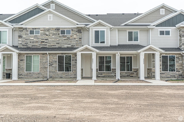 townhome / multi-family property featuring board and batten siding, roof with shingles, covered porch, and stone siding