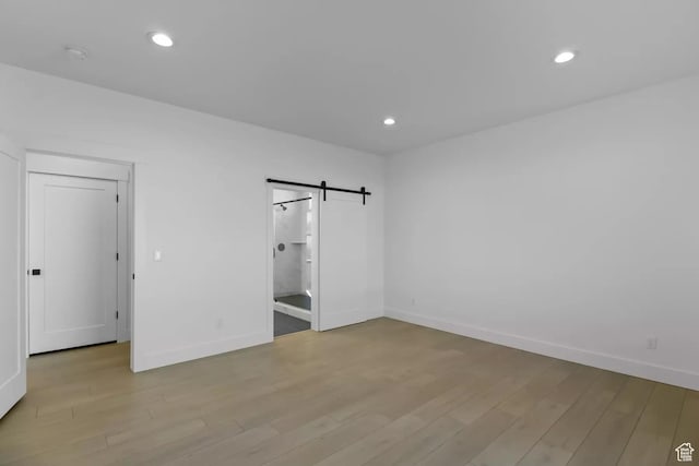 5291 W 3775 S Unit 22, Hooper, UT 84315 - unfurnished bedroom with a barn door and light hardwood / wood-style floors