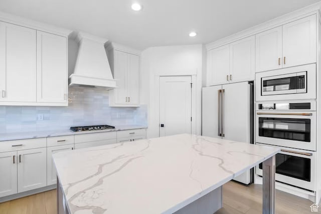 5291 W 3775 S Unit 22, Hooper, UT 84315 - kitchen featuring appliances with stainless steel finishes, backsplash, light stone countertops, custom range hood, and white cabinets
