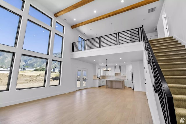 5291 W 3775 S Unit 22, Hooper, UT 84315 - unfurnished living room featuring an inviting chandelier, a high ceiling, french doors, beamed ceiling, and light wood-type flooring