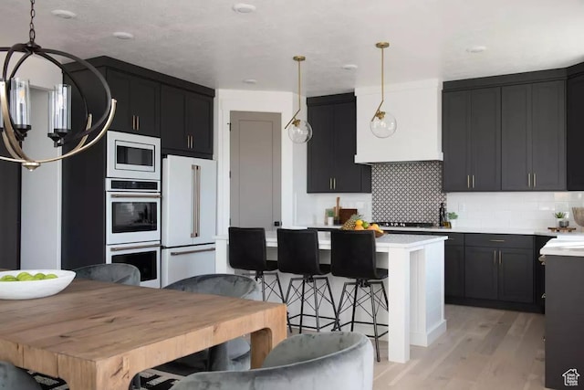 5291 W 3775 S Unit 22, Hooper, UT 84315 - kitchen with a kitchen island, decorative light fixtures, decorative backsplash, white appliances, and light wood-type flooring