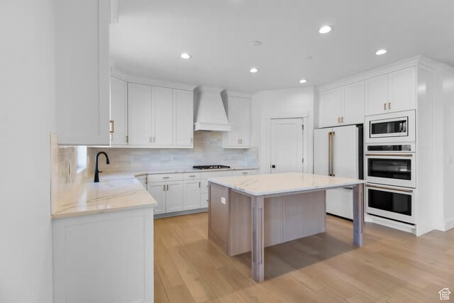 5291 W 3775 S Unit 22, Hooper, UT 84315 - kitchen with wall chimney exhaust hood, sink, built in appliances, a center island, and white cabinets