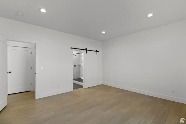 5291 W 3775 S Unit 22, Hooper, UT 84315 - unfurnished bedroom with a barn door and light hardwood / wood-style flooring