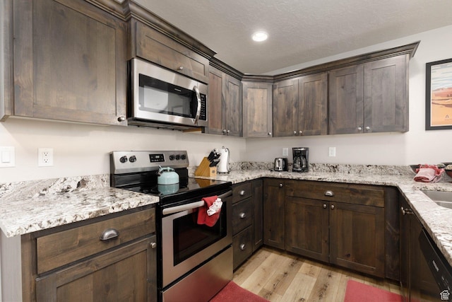 717 S 775 W, Hurricane, UT 84737 - kitchen with a textured ceiling, dark brown cabinets, light wood-type flooring, appliances with stainless steel finishes, and light stone countertops
