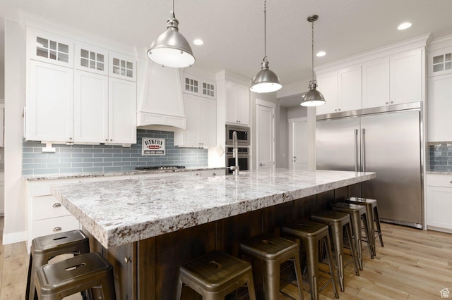 717 S 775 W, Hurricane, UT 84737 - kitchen featuring a breakfast bar, white cabinets, built in appliances, custom range hood, and a spacious island