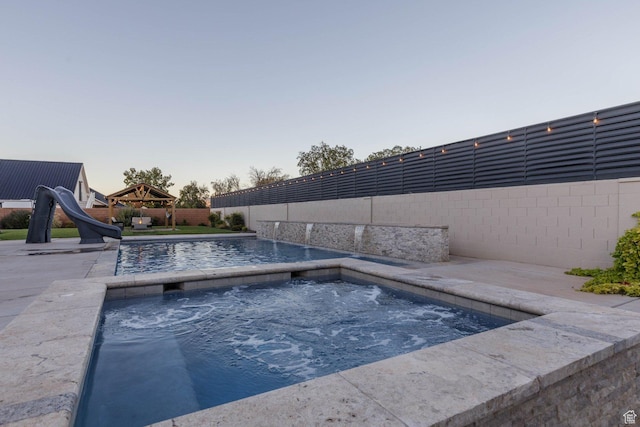 717 S 775 W, Hurricane, UT 84737 - pool at dusk featuring an in ground hot tub, a water slide, a gazebo, and pool water feature