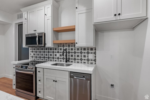 310 S Autumn Blaze Cir, Woodland Hills, UT 84653 - kitchen featuring sink, white cabinetry, light wood-type flooring, appliances with stainless steel finishes, and decorative backsplash