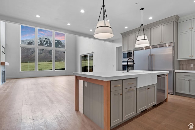 310 S Autumn Blaze Cir, Woodland Hills, UT 84653 - kitchen featuring gray cabinets, pendant lighting, stainless steel appliances, a center island with sink, and light hardwood / wood-style flooring