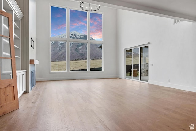 310 S Autumn Blaze Cir, Woodland Hills, UT 84653 - unfurnished living room featuring a healthy amount of sunlight, a notable chandelier, and light wood-type flooring