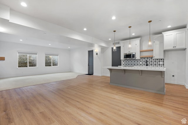 310 S Autumn Blaze Cir, Woodland Hills, UT 84653 - kitchen featuring tasteful backsplash, white cabinetry, a kitchen bar, hanging light fixtures, and a large island
