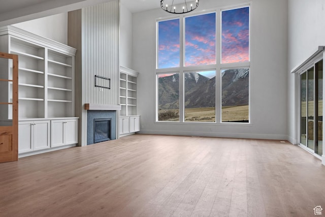 310 S Autumn Blaze Cir, Woodland Hills, UT 84653 - unfurnished living room with a chandelier, light wood-type flooring, a large fireplace, a mountain view, and a high ceiling