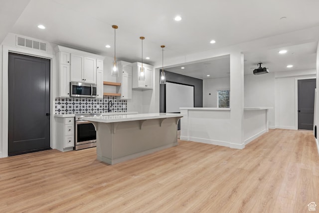 310 S Autumn Blaze Cir, Woodland Hills, UT 84653 - kitchen featuring a breakfast bar, appliances with stainless steel finishes, white cabinetry, hanging light fixtures, and light wood-type flooring