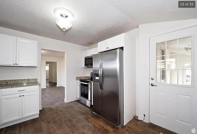 kitchen with dark wood-type flooring, appliances with stainless steel finishes, stone countertops, and white cabinets