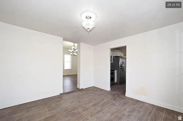 spare room with a notable chandelier and dark hardwood / wood-style floors