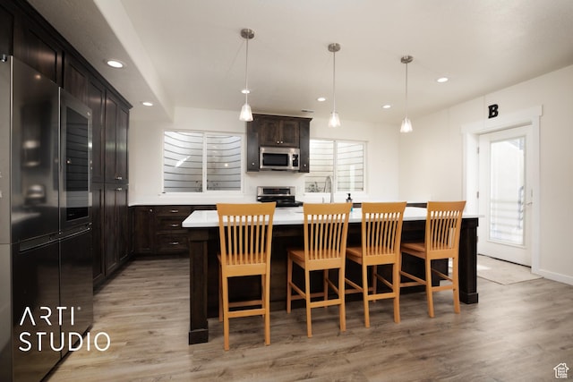 429 W Olympic Ln, Elk Ridge, UT 84651 - kitchen with a breakfast bar area, stainless steel appliances, recessed lighting, light countertops, and light wood-style floors
