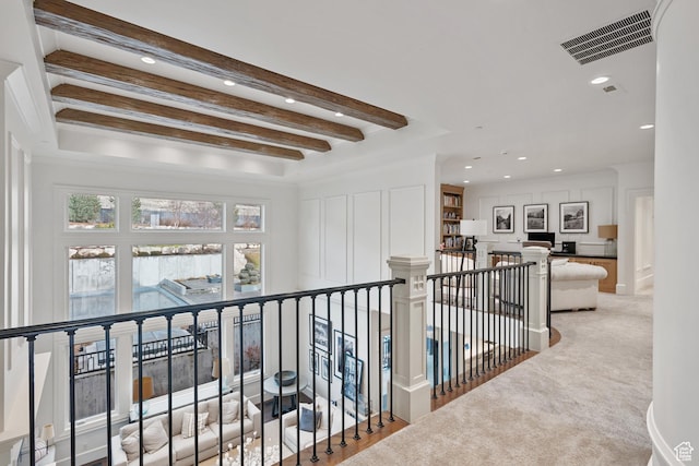 hallway with light colored carpet and beam ceiling