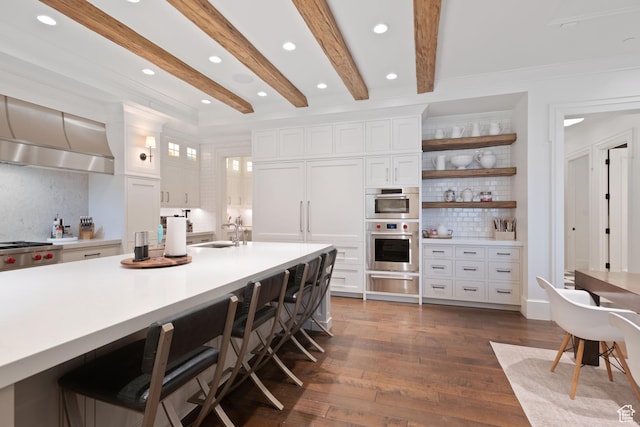 kitchen with dark hardwood / wood-style floors, a breakfast bar area, white cabinets, and beam ceiling