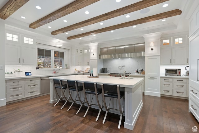 kitchen with sink, a breakfast bar area, white cabinets, stainless steel dishwasher, and a spacious island