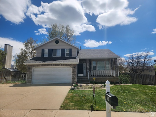 tri-level home with a porch, concrete driveway, fence, an attached garage, and a front yard