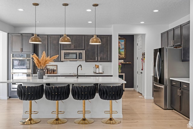kitchen with hanging light fixtures, appliances with stainless steel finishes, sink, and a kitchen bar