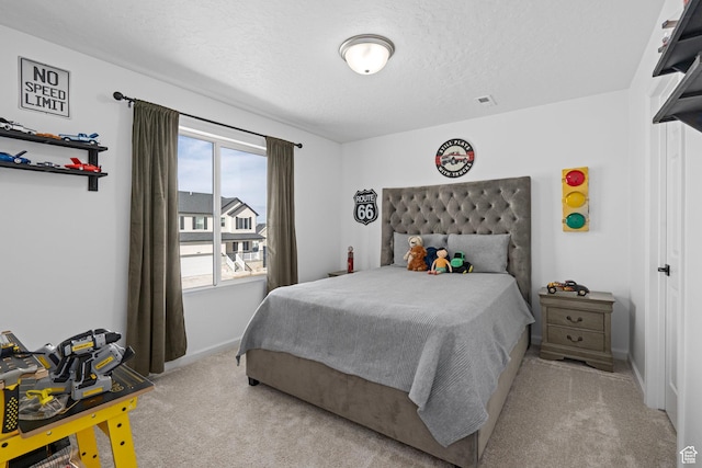 bedroom with light colored carpet and a textured ceiling
