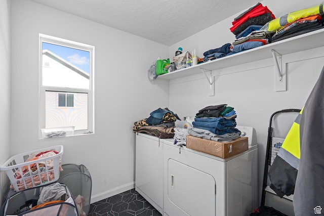 washroom with dark tile patterned flooring, washing machine and dryer, and a textured ceiling