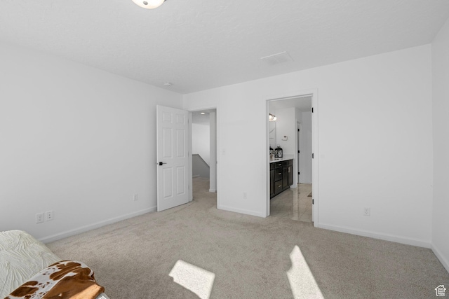 unfurnished bedroom with ensuite bathroom and light colored carpet