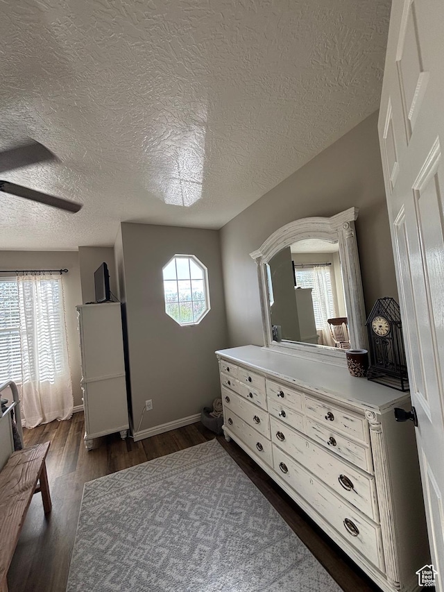 bedroom with dark wood-style flooring, a textured ceiling, a ceiling fan, and baseboards