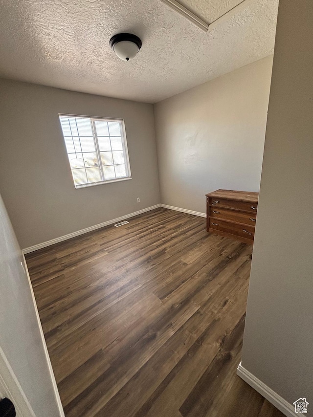 unfurnished room featuring dark wood-style floors, baseboards, and a textured ceiling