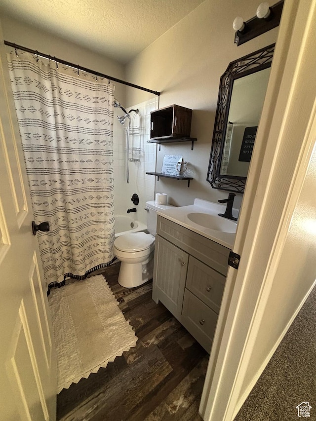 full bath featuring wood finished floors, a textured ceiling, vanity, toilet, and shower / bath combination with curtain