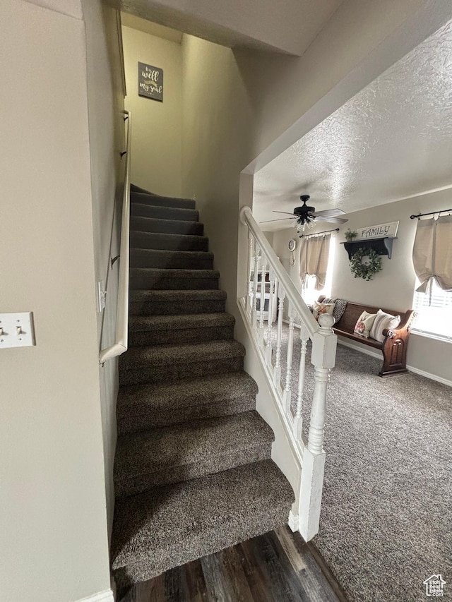 staircase with a textured ceiling, ceiling fan, wood finished floors, and baseboards