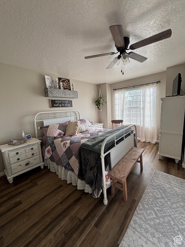 bedroom with dark wood-type flooring, a textured ceiling, and a ceiling fan
