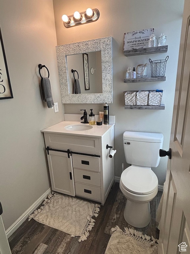 bathroom featuring wood finished floors, vanity, toilet, and baseboards
