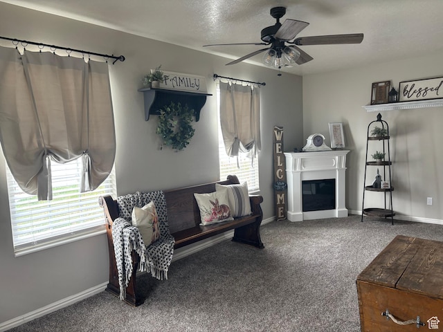 living area featuring carpet, ceiling fan, a glass covered fireplace, and baseboards
