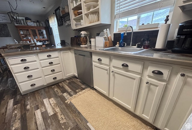 kitchen featuring dishwasher, a sink, a peninsula, dark wood-style floors, and white cabinets