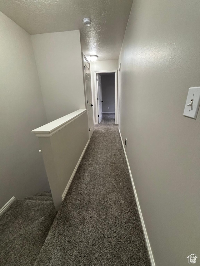 hall with an upstairs landing, carpet flooring, a textured ceiling, and baseboards
