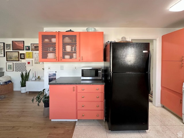 2220 E Murray Holladay Rd Unit 140, Holladay, UT 84117 - kitchen featuring freestanding refrigerator, stainless steel microwave, red cabinetry, and dark countertops