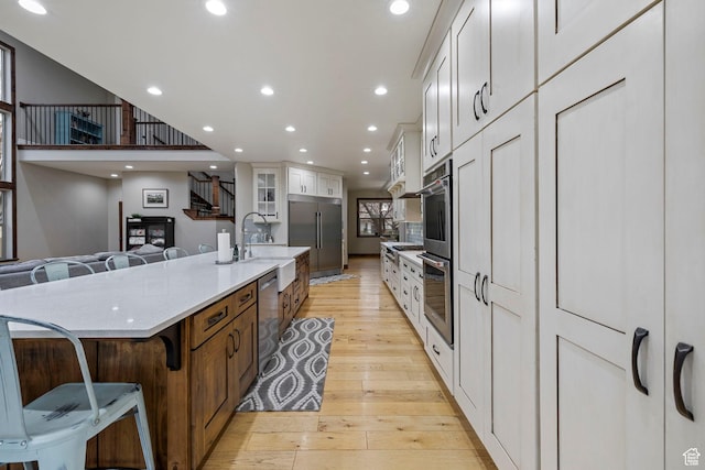 1532 W 3500 N, Pleasant Grove, UT 84062 - kitchen with stainless steel appliances, light wood finished floors, a kitchen breakfast bar, white cabinets, and glass insert cabinets