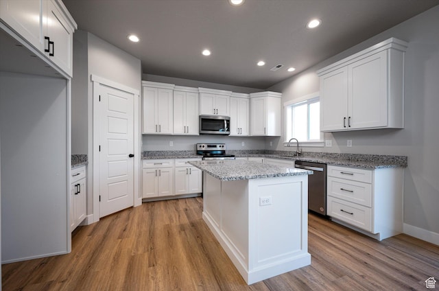 1357 N 450 W Unit 50, Brigham City, UT 84302 - kitchen featuring appliances with stainless steel finishes, a center island, light stone counters, white cabinets, and light wood-type flooring