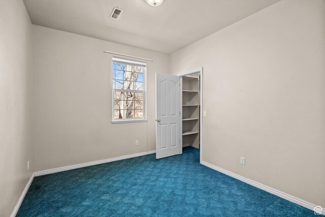 567 S 400 E, Moab, UT 84532 - unfurnished bedroom with baseboards, dark carpet, and a walk in closet