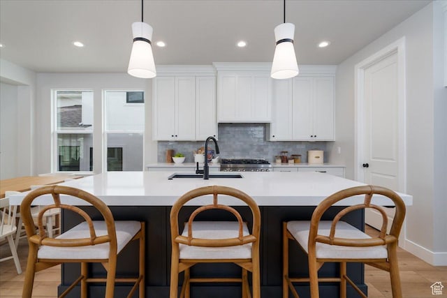 2998 N 1080 W, Lehi, UT 84043 - kitchen featuring backsplash, light countertops, a sink, and a kitchen island with sink