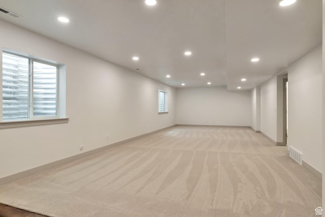 basement featuring baseboards, light carpet, recessed lighting, and visible vents