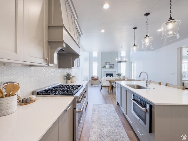 kitchen with a sink, dark wood finished floors, high end range, wall oven, and a healthy amount of sunlight