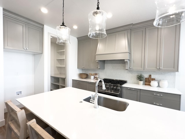 kitchen with decorative backsplash, pendant lighting, a kitchen breakfast bar, light countertops, and gray cabinets