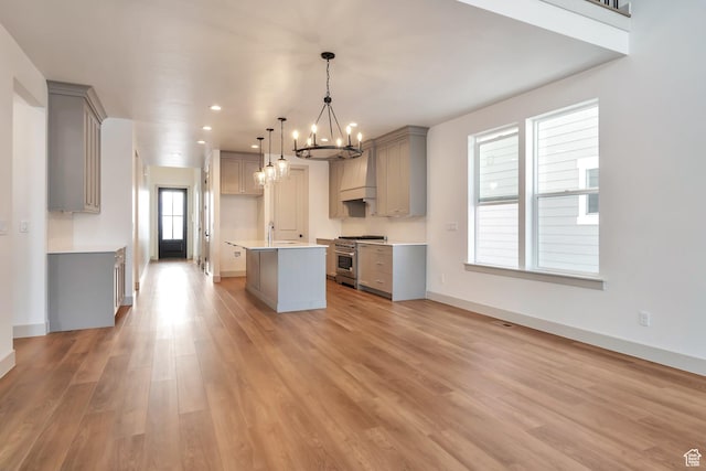 kitchen with an inviting chandelier, high end stainless steel range, baseboards, light wood-type flooring, and gray cabinets