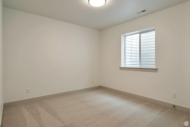 spare room featuring light colored carpet, baseboards, and visible vents