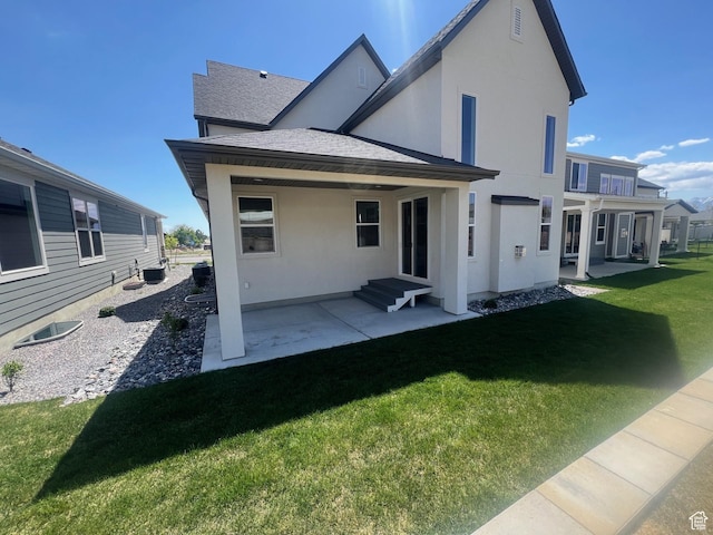 back of property with roof with shingles, central air condition unit, stucco siding, a patio area, and a lawn