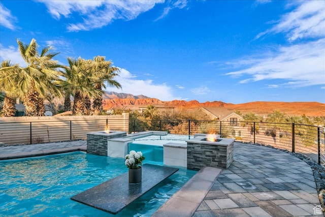 view of swimming pool featuring an outdoor fire pit, a mountain view, and a patio